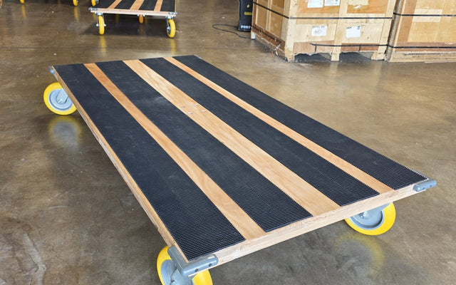 Solo CasterHQ kiln-dried oak platform cart with yellow casters and black conveyor-belt grip strips in Mansfield Texas warehouse
