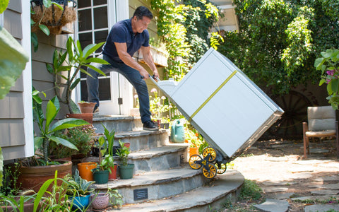 Stair-climbing hand truck moving an appliance on outdoor steps, illustrative of a hand truck type, not AD case merchandise