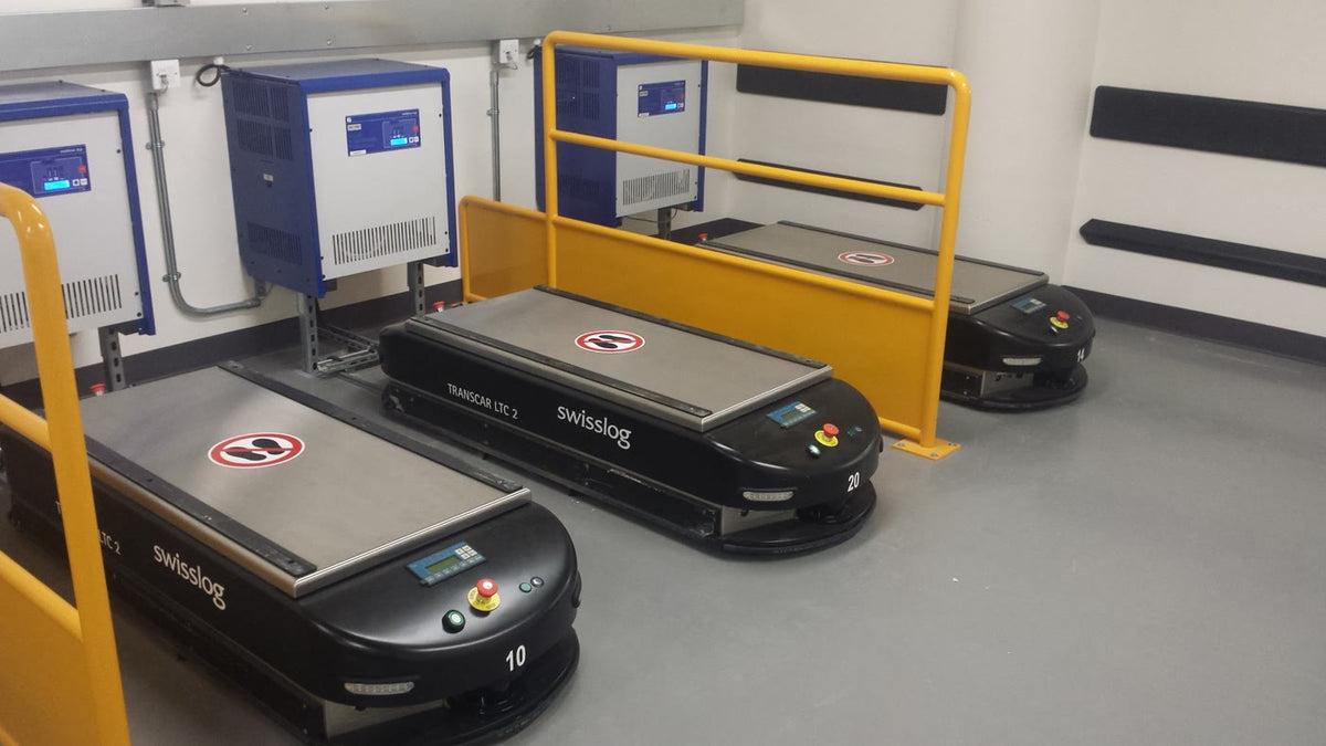 Stand-in warehouse automated guided vehicles — illustrative only, not Cummins Lindesberg or KNAPP Open Shuttle Fork hardware