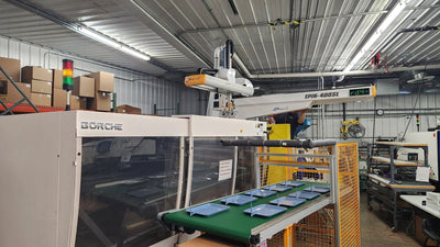 Injection molding machine with robot arm and conveyor trays, illustrative manufacturing cell, not the Tiffin Kreate plant
