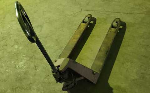 Manually propelled pallet jack on a concrete floor, illustrative of a low-lift type, not an ITSDF test
